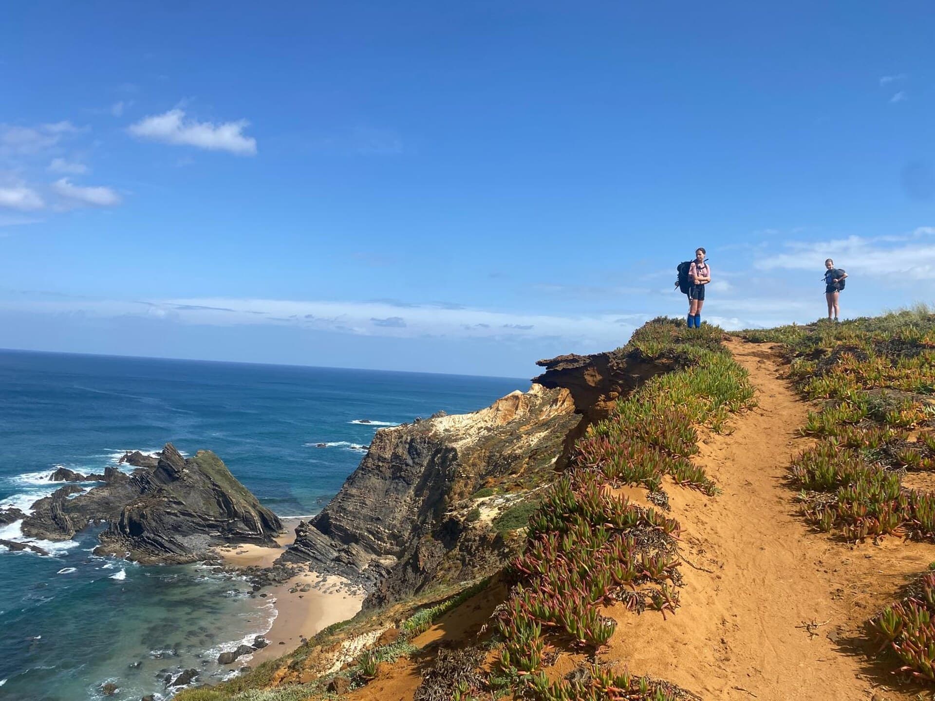 A parent and child pausing on a clifftop above the Atlantic on the Fishermen's Trail